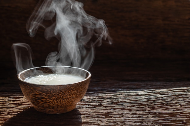 Foto vapor de mush ou arroz cozido estilo asiático com fumaça na tigela de madeira no fundo escuro