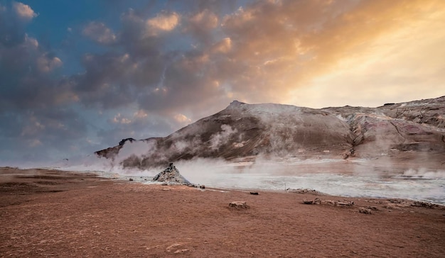 Vapor emitindo da cratera na área geotérmica de hverir contra o céu durante o pôr do sol