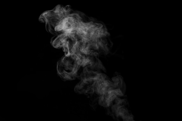 El vapor de humo denso rizado blanco que se eleva está aislado en un fondo negro para superponer sus fotos