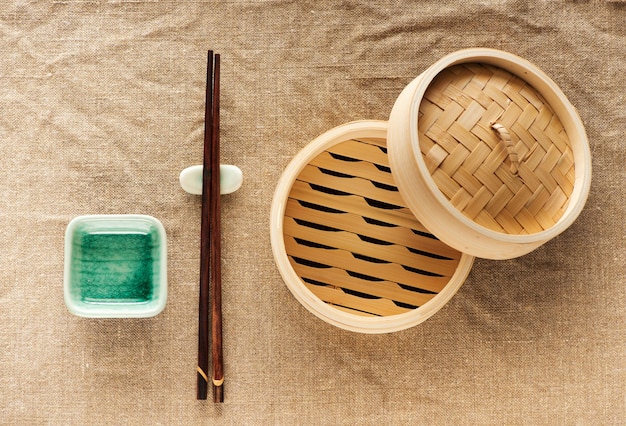 Vaporizador de bambu e pauzinhos em fundo de serapilheira. jogo de utensílios de cozinha asiáticos