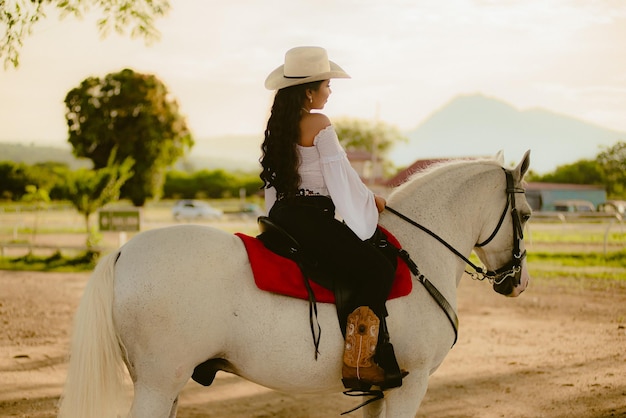 Vaqueira vestida de branco com um cavalo branco