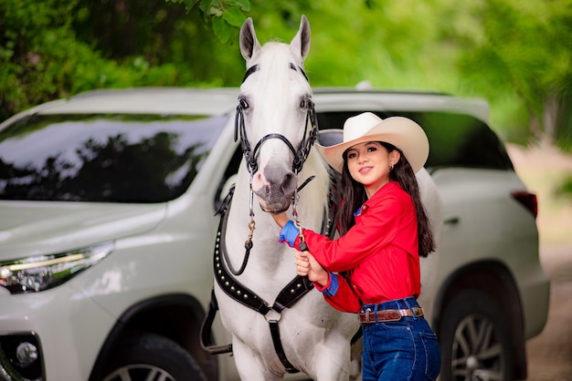 Foto vaquera sonriendo mientras camina junto a su caballo blanco