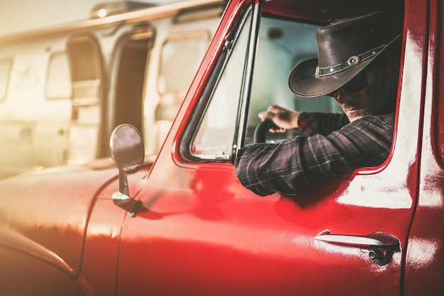 Vaquero en una camioneta clásica junto a su remolque de viaje