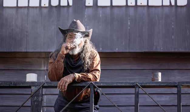 Un vaquero fuma una pipa de tabaco con un sombrero de ala ancha y una diadema.