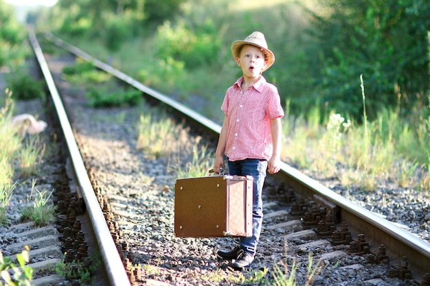 Vaquero de niño sorprendido con concepto de viaje occidental de maleta y ferrocarril