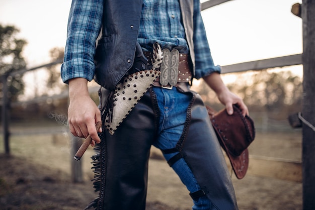 Vaquero en ropa de cuero posa con cigarrillos