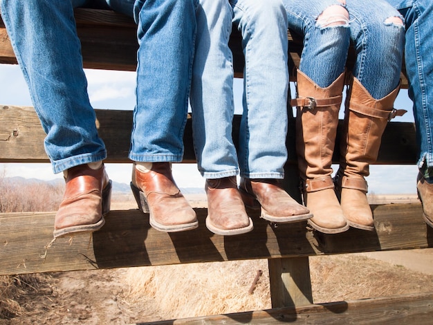 Vaqueros y vaqueras sentados en la valla de madera.