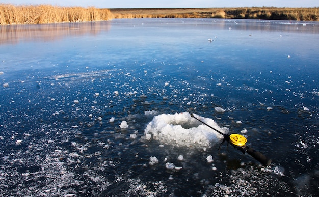 Vara de pesca de inverno deitado no gelo perto do buraco