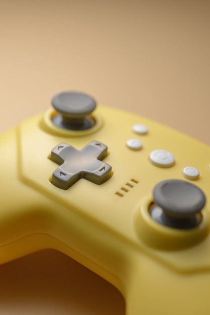 Vara de um close-up de controlador de jogo amarelo. Videogames, entretenimento em casa. Close-up de botões amarelos no joystick sem fio. Conceito de jogo móvel.