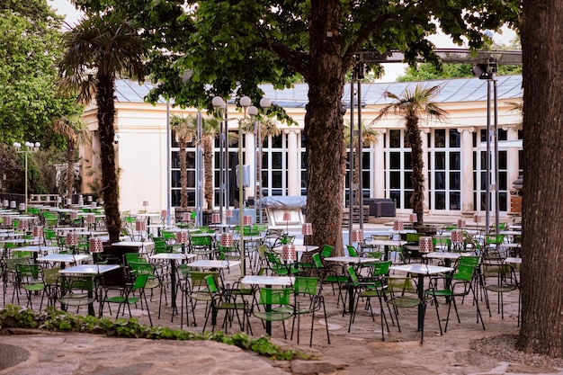 Varanda de café de rua típica ao ar livre no centro da cidade velha em Viena, na Áustria. Lugar de restaurante com mesas e cadeiras em Viena. Bar da cidade austríaca e cafeteria sob palmeiras em noite romântica