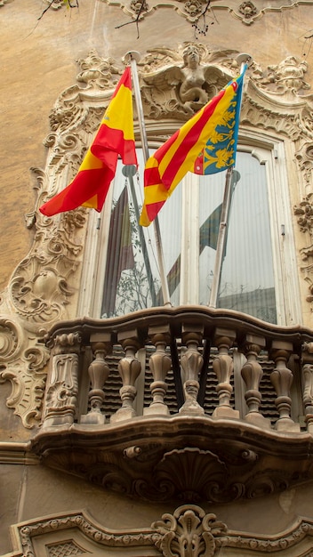 Varanda de um edifício histórico na cidade de Valência, Espanha, com as bandeiras de Valência e Espanha acenando