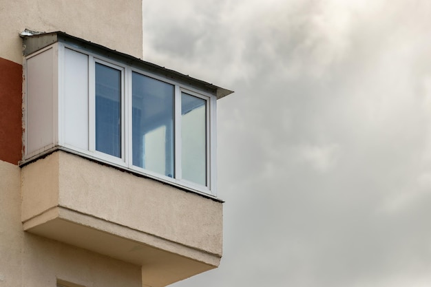 Varanda envidraçada na fachada do edifício contra o fundo de nuvens cinzentas no céu