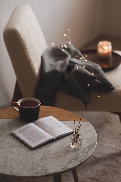 Foto varas de bambu em garrafa com velas perfumadas com xícara de chá e livro aberto na mesa de mármore closeup aroma em casa aromaterapia apartamento vivendo