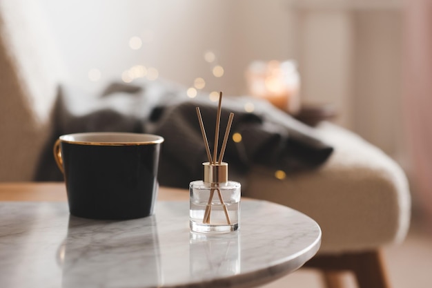 Varas de bambu em garrafa com velas perfumadas e xícara de chá na mesa de mármore closeup Aroma em casa Aromaterapia Apartamento vivendo