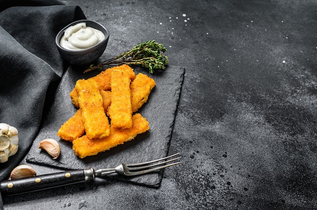 Varas de peixe esmigalhadas assadas forno feitas de peixe branco na tabela preta.