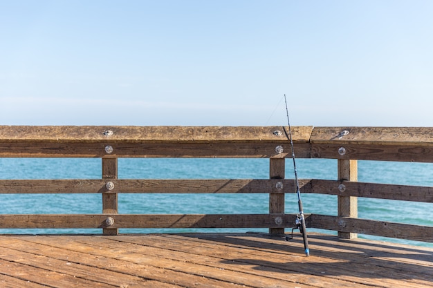 Varas de pesca, apoiando-se em um trilho em um cais em Ventura Los Angeles Califórnia