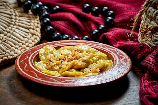 Varenyky ucraniano tradicional relleno de carne y cebolla frita en platos de arcilla Cocina ucraniana Cerrar