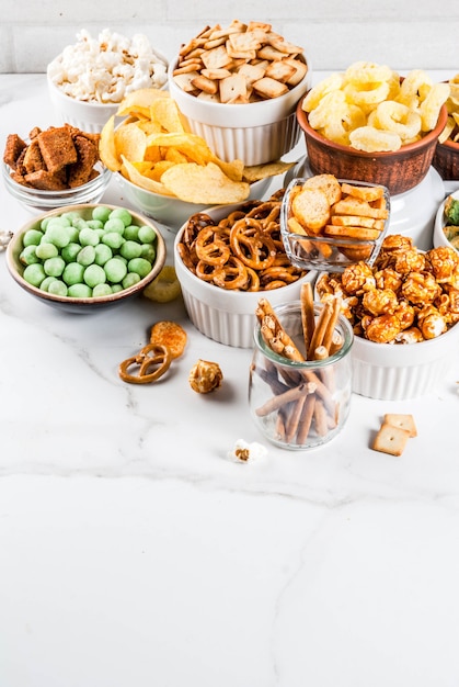 Variação diferentes biscoitos salgadinhos insalubres, pipoca salgada doce, tortilhas, nozes, palhas, bretsels