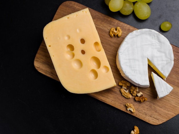 Variación de queso, nueces y uvas en tabla de cortar de madera. Queso Camembert y queso Edam. Comida para vino y romántica, desde la vista superior.