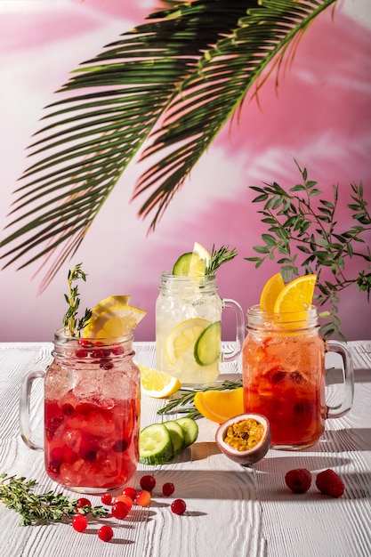 Variações de limonadas com diferentes frutas e xaropes na mesa de madeira sob o sol da manhã