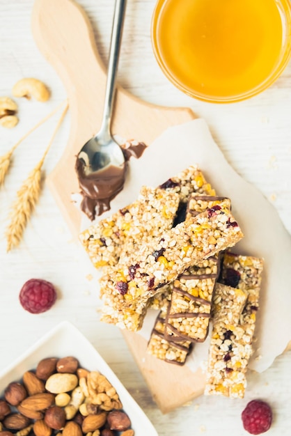 Várias barras de granola caseiras com sementes de nozes, mel de chocolate escuro e bagas sobre uma placa de madeira