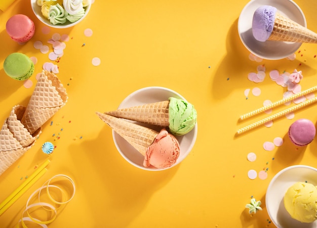 Varias bolas de helado de colores o bolas con conos de gofre sobre fondo amarillo Vista superior