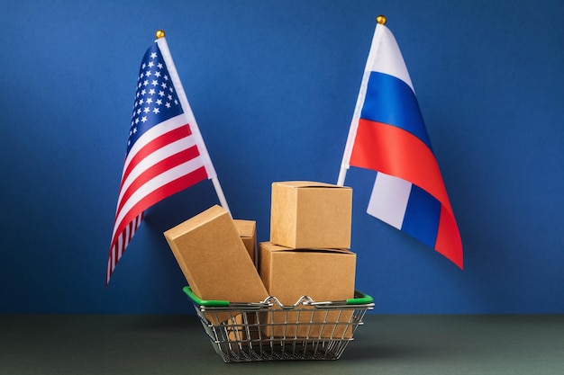 Foto varias cajas en una canasta de alimentos y dos banderas el concepto de comercio entre estados unidos y rusia