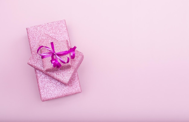 Varias cajas de regalo se encuentran una encima de la otra sobre un fondo rosa con espacio para copiar