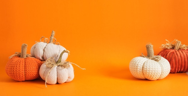 Varias calabazas caseras para la decoración navideña de Halloween tejidas y calabazas de tela sobre fondo naranja