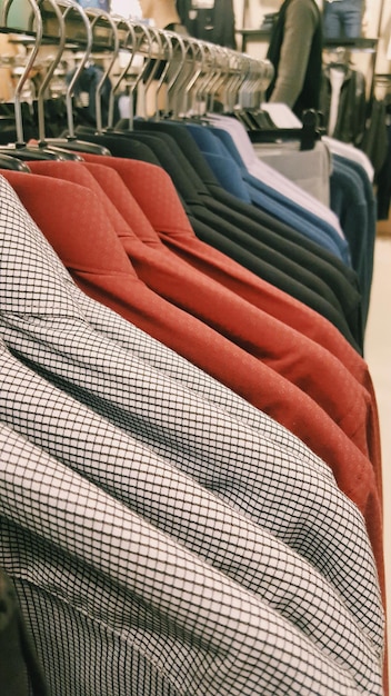 Varias camisas colgando en el estante para la venta en la tienda