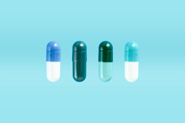 Varias cápsulas de almidón duro de dos piezas sobre fondo azul Aditivos biológicamente activos Concepto de salud