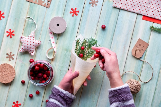 Várias decorações ecológicas de férias de inverno de natal ou ano novo, pacotes de papel ofício e presentes reutilizáveis ou com zero desperdícios. postura plana em tábuas de madeira, amora em cone de madeira compensada com folhas verdes.