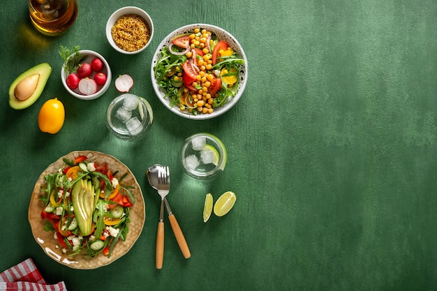 Foto varias ensaladas de verduras saludables de verano con aguacate, pepino, rábano, pimiento y tomate sobre fondo verde. comida sana vista superior.