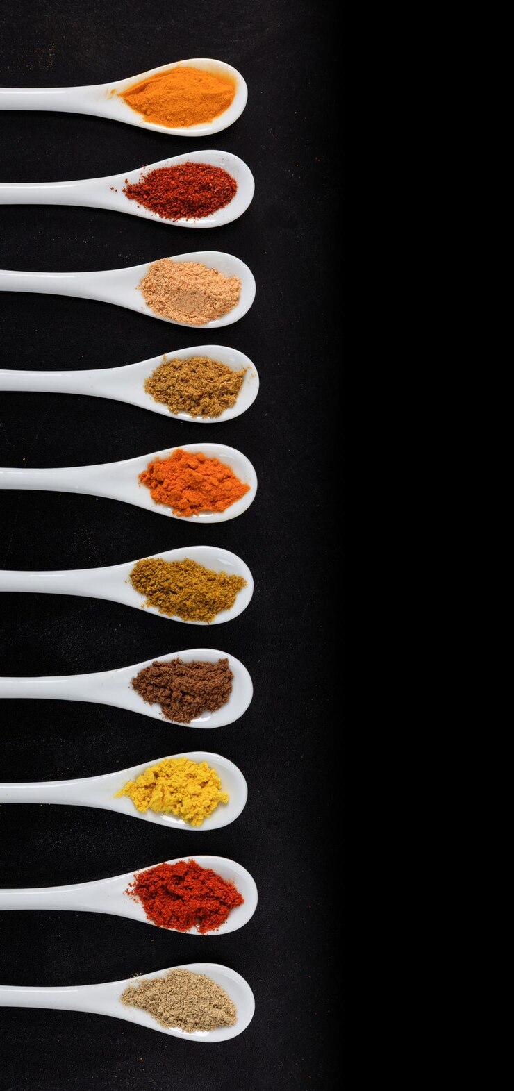 Varias especias en cucharas de porcelana vista superior