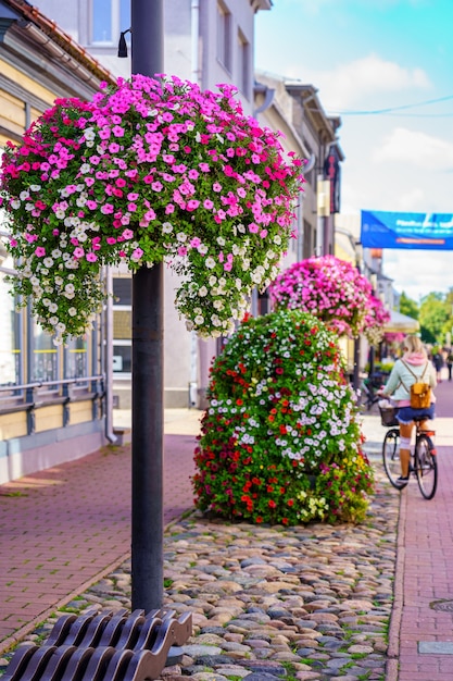 Varias flores decoran las calles de la ciudad con una mujer en bicicleta.