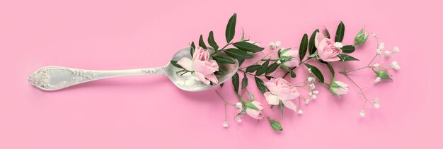 Várias flores delicadas em uma colher em um fundo rosa. conceito de bebida aromática