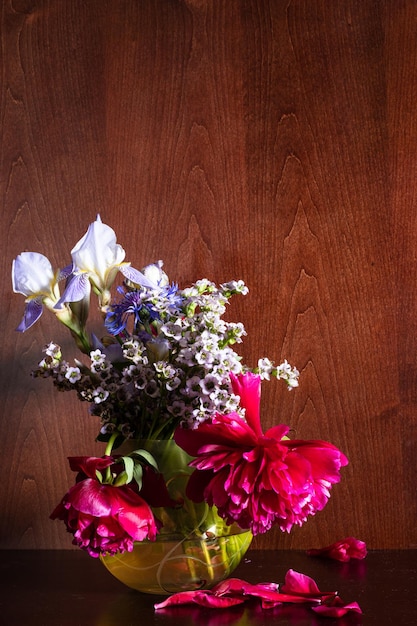 Varias flores en jarrón sobre fondo marrón oscuro