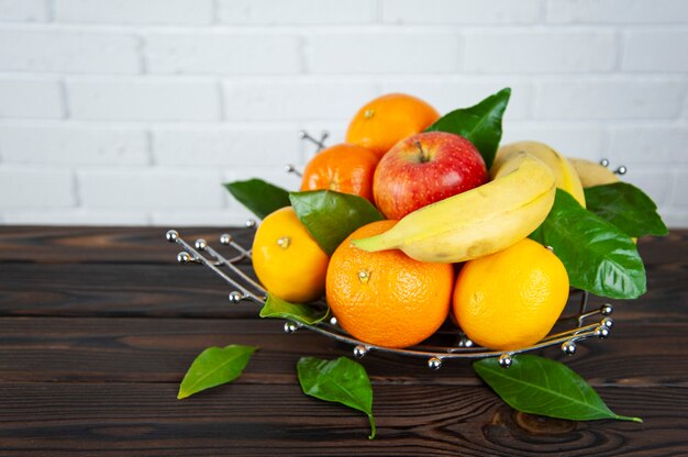 Varias frutas en un frutero de metal sobre una superficie de madera