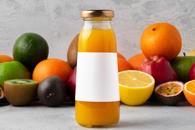 Foto varias frutas y jugo de frutas recién exprimido en botella sobre fondo gris