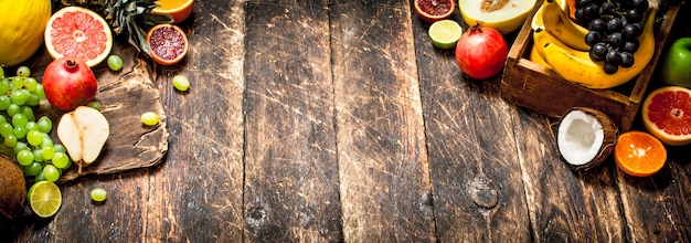 Varias frutas maduras en una caja de madera sobre mesa de madera.