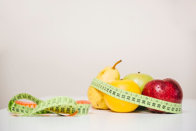 Foto varias frutas sanas y cinta métrica en la mesa