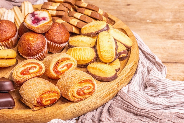 Varias galletas y muffins surtidos. Placa de combinación de madera en la mesa de tableros antiguos, cerrar