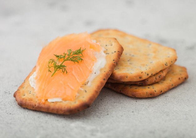 Varias galletas saladas saludables con crema y salmón en la mesa de la cocina ligera