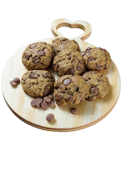 Varias galletas en una tabla redonda de madera con el corazón Junto a callets de chocolate_foto vertical