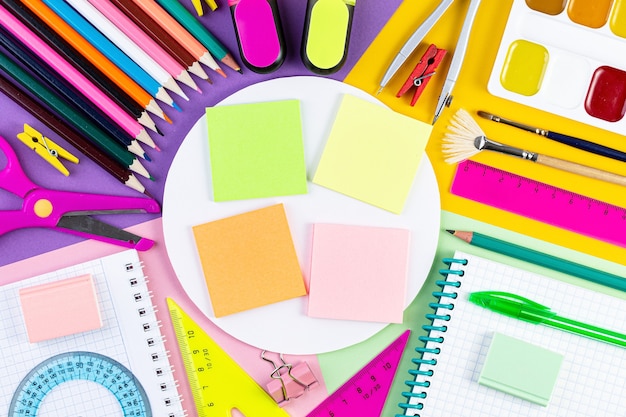 Varias herramientas de escritura en la superficie del papel de colores.
