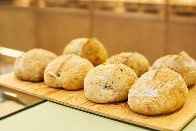 Varias hogazas de pan en tablero de madera o bandeja en exhibición o mostrador