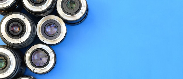 Varias lentes fotográficas se encuentran sobre un fondo azul brillante. Espacio para texto