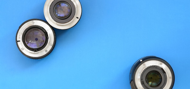 Varias lentes fotográficas se encuentran sobre un fondo azul brillante.