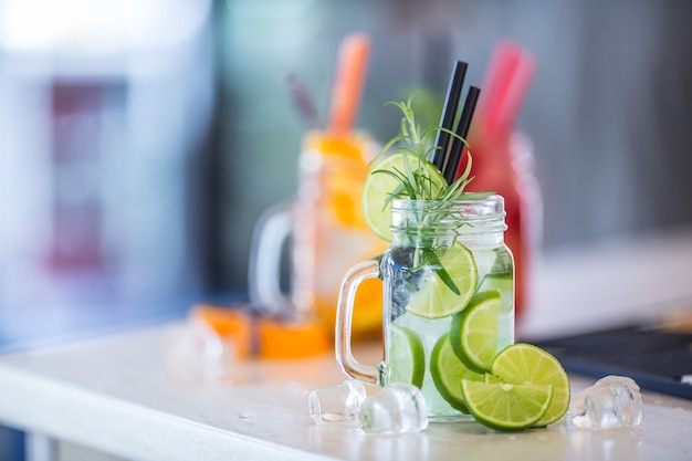 Várias limonadas em potes de vidro com laranja lima, limão, morangos otange e frutas frescas.