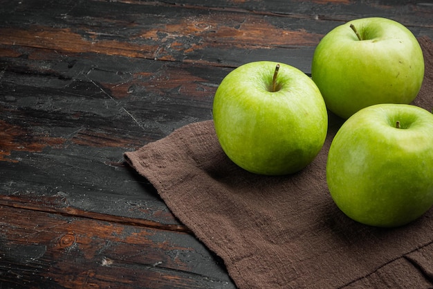 Varias manzanas verdes maduras en el fondo de una mesa rústica oscura antigua con espacio para copiar texto